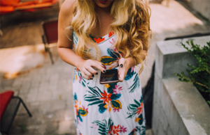 Blonde girl holding phone in a floral dress